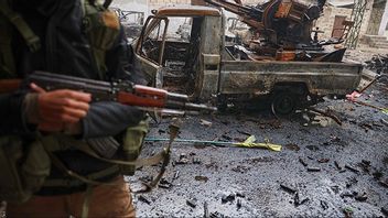 Syrisk regimsoldat poserar vid förstört fordon under striderna i Aleppo. Bild: AP Photo/Omar Albam