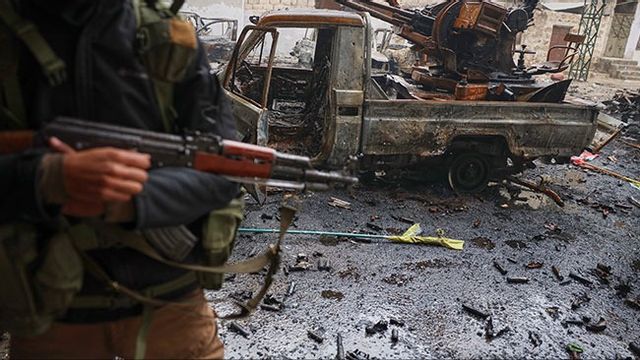 Syrisk regimsoldat poserar vid förstört fordon under striderna i Aleppo. Bild: AP Photo/Omar Albam