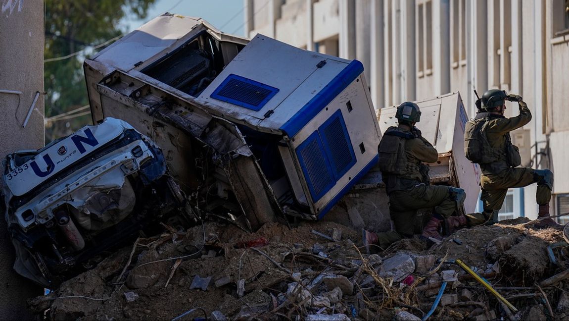 Israeliska soldater söker skydd bakom förstörda fordon från UNRWA. Platsen är en FN-anläggning som låg ovanpå de tunnlar som Hamas använde för att anfalla Israel. Foto: Ariel Schalit/AP/TT