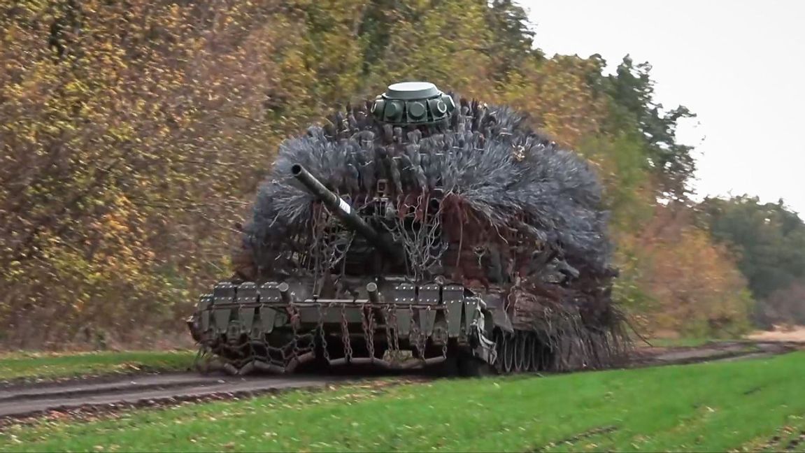 En rysk stridsvagn som försetts med metall nästan som ett piggsvin för att troligen mildra effekterna av träffar från kamikazedrönare, rullar fram för att skjuta mot de ukrainska linjerna i en video från det ryska försvarsministeriet. Foto: Rysslands försvarsministeriums presstjänst via AP