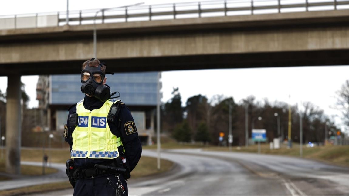 Polis i gasmask vid Säkerhetspolisens högkvarter i Solna norr om Stockholm. Foto: Fredrik Persson/TT