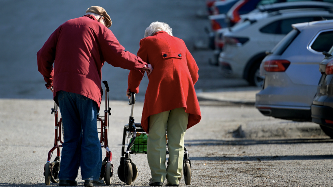 Äldre par på promenad med rullator på en parkeringsplats i Huvudsta. Foto: Janerik Henriksson / TT