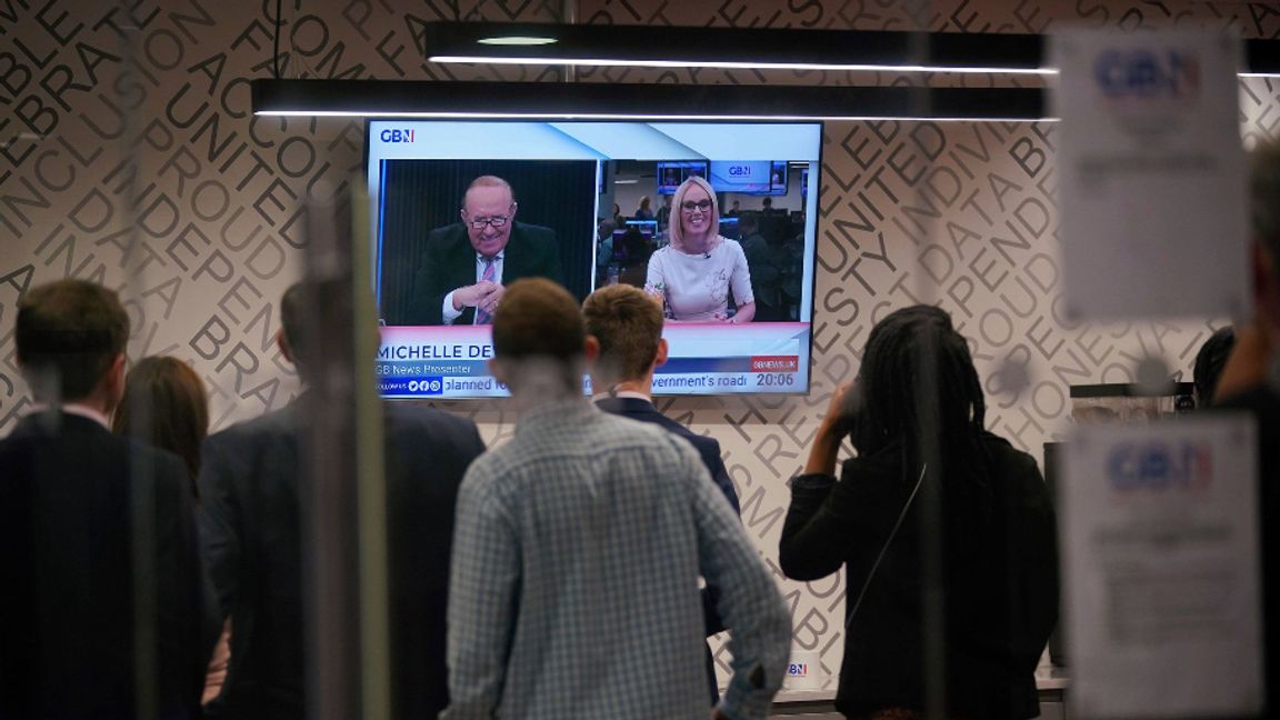 Personal i GB News green room tittar på söndagens premiärsändning. Foto: AP/TT.