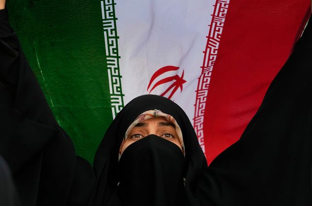 Iransk kvinna som håller upp sitt lands flagga under en regimvänlig demonstration i Teheran, tisdagen 24 juni, medan regimkritiker löper ökad risk att fängslas. Foto: Vahid Salemi/AP/TT