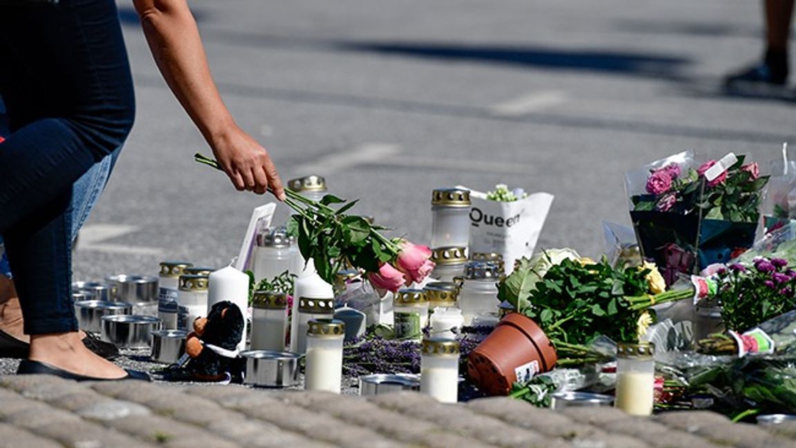 Folk samlas vid blommorna och ljusen på platsen där en 12-årig flicka sköts ihjäl vid en bensinmack i Botkyrka i augusti förra året. Foto: Stina Stjernkvist/TT