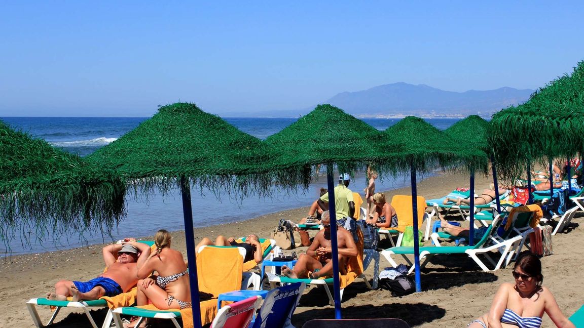 Turister solar på solstolar under parasoll på en badstrand i Marbella i Spanien. Foto Tina Remius Strömberg / TT