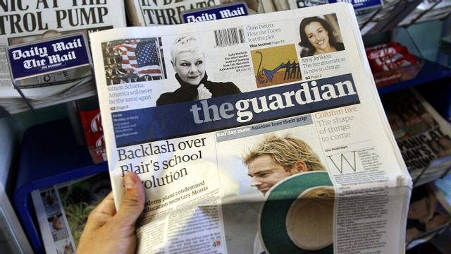 En person som håller i tidningen The Guardian. Foto: Lefteris Pitarakis/AP/TT