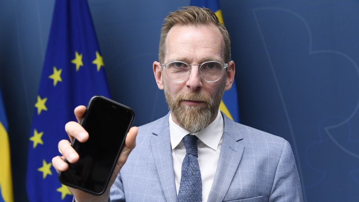 Socialminister Jakob Forssmed håller upp en mobiltelefon på en pressträff om skärmtid bland barn och unga. Foto: Marko Säävälä/TT