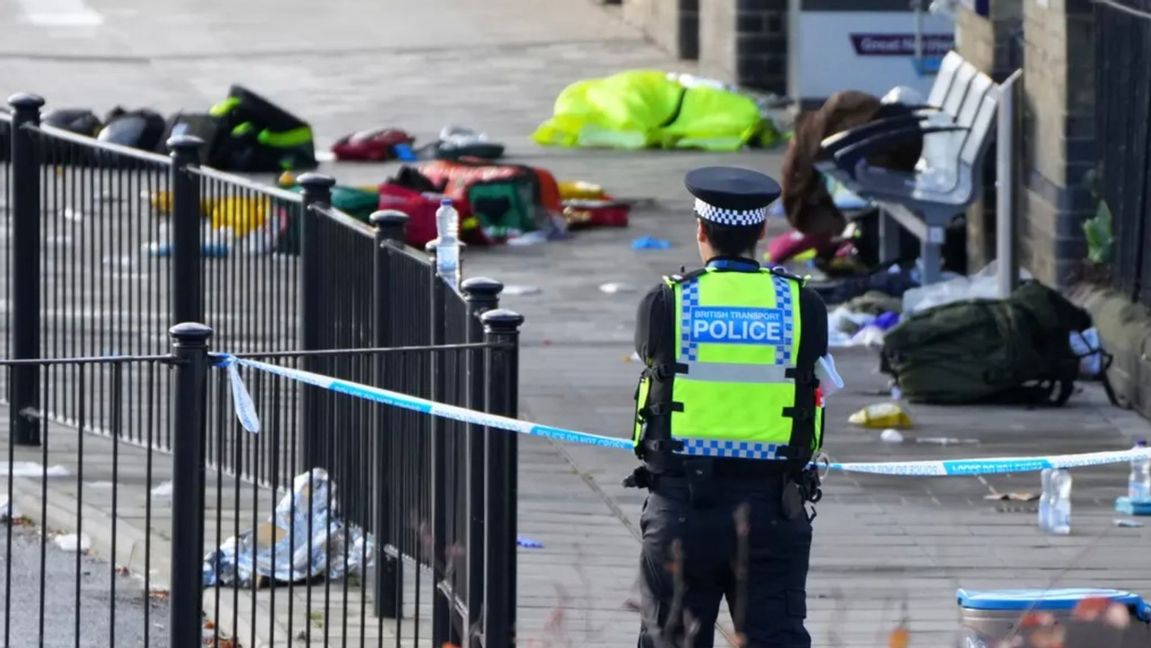 En polis övervakar platsen där flyende resande lämnat sina tillhörigheter på Huntingdon station Foto: Kirsty Wigglesworth/AP/TT