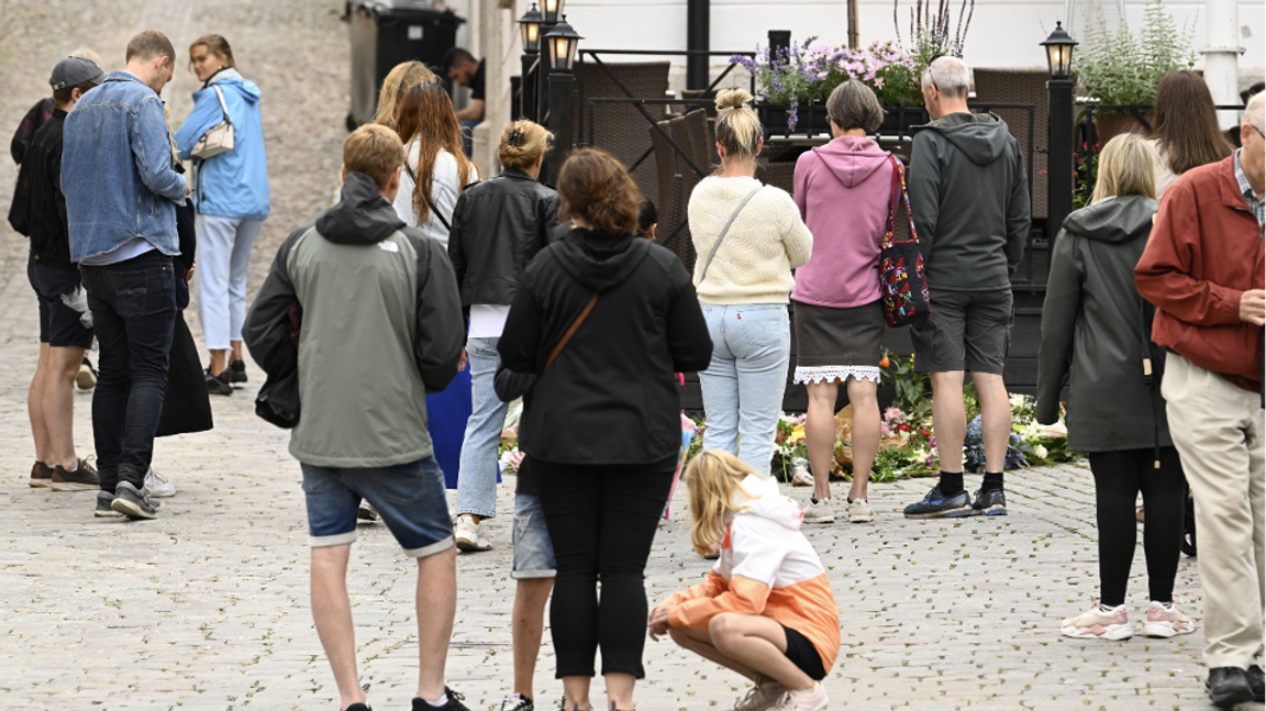 Personer lägger ner blommor vid platsen där en gärningsman attackerade och dödade en kvinna vid Donners plats i Visby under Almedalsveckan förra året. Foto Henrik Montgomery / TT 