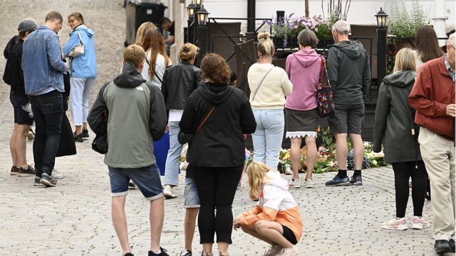 Personer lägger ner blommor vid platsen där en gärningsman attackerade och dödade en kvinna vid Donners plats i Visby under Almedalsveckan förra året. Foto Henrik Montgomery / TT