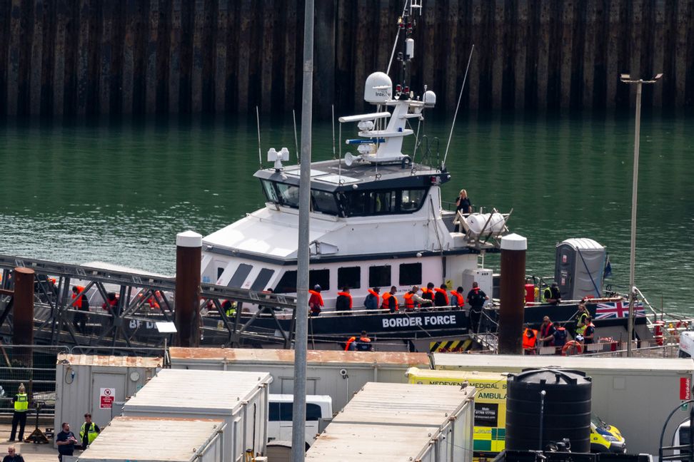 Människor som plockats upp vid ett båthaveri i Engelska kanalen anländer till hamnen i brittiska Dover med ett fartyg från den brittiska gränspolisen. Bilden togs den 14 augusti. Jordan Pettitt/PA via AP/TT