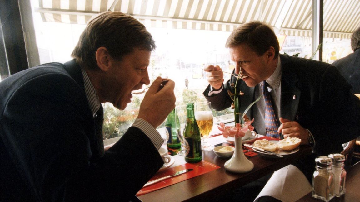Affärsmän i full färd med att äta soppa på sin lunch. En av dem gapar med skeden mot munnen. Maten framdukad på restaurangbordet. Uppskuren småfranska på en assiett och ölflaskor. Foto: Dan Hansson/SCANPIX