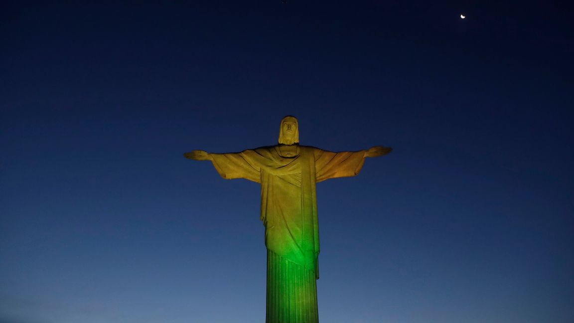 Karnevalen i Rio de Janeiro ställs in, då det inte bedöms vara möjligt heller i juli. Här har Jesusstatyn på den så kallade Sockertoppen lysts upp för att markera vaccinstarten tidigare i veckan. Foto: Bruna Prado/AP/TT