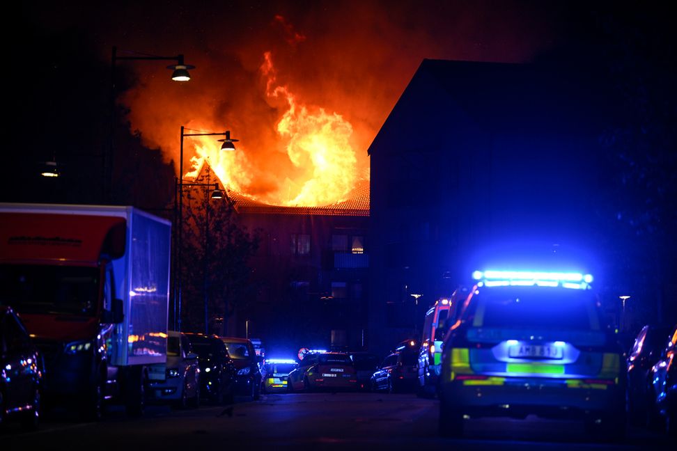 Räddningstjänsten arbetar med att bekämpa en kraftig brand i ett flerfamiljshus i Upplands-Bro norr om Stockholm på fredagskvällen. Foto: Oscar Olsson/TT