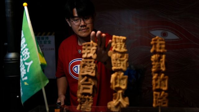 En försäljare visar stöd för det styrande partiet DPP och dess presidentkandidat Lai Ching-Te genom att sälja bakverk med partiets kampanjslogans. Foto: NG HAN GUAN/AP/TT