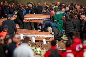 En person gråter och lutar sig över en kista under torsdagens begravningsceremoni för de som omkom i nattklubbsbranden i Nordmakedonien. Foto: Visar Kryeziu/AP/TT