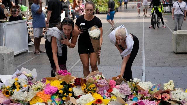 Tre kvinnor lägger blommor nära köpcentrumet i östra Sydney söndagen den 14 april, efter att flera personer knivhuggits till döds dagen innan. Foto: Rick Rycroft/AP/TT