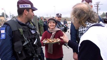 En demonstrant för Palestina blir bjuden på kakor av en israelisk kvinna Foto: Karel Prinsloo/AP/TT