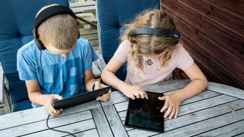 Barn sitter och spelar på surfplattor en sommardag. Foto: Christine Olsson / TT /