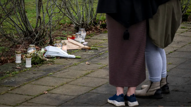 Invånare lämnar blommor och ljus utanför det avspärrade området där en kvinna och ett tioårigt barn hittades döda i ett misstänkt dubbelmord. Foto: Johan Nilsson/TT