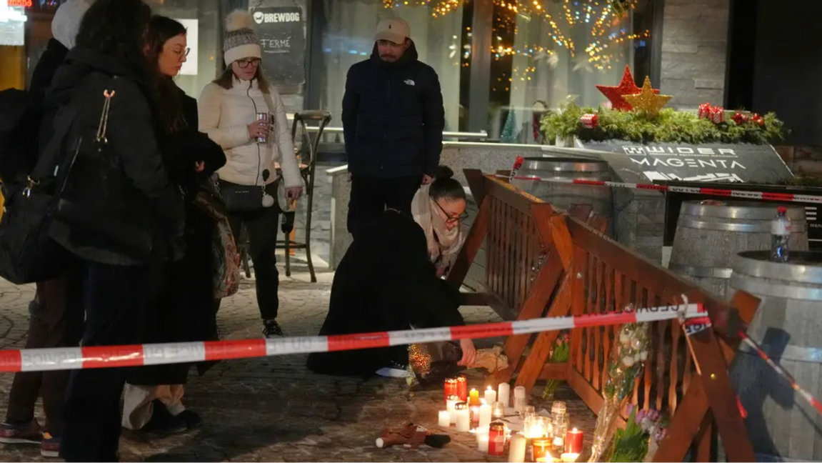 Människor tänder ljus för offren i dödsbranden på skidortsbaren Le Constellation. Foto: Antonio Calanni/AP/TT