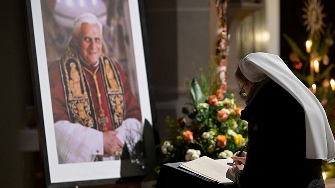 En kvinna skriver i en kondoleansbok för påve Benedictus. Foto: Andreas Schaad/AP/TT