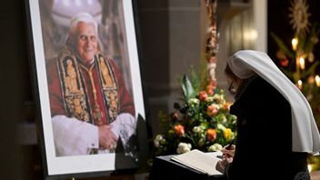 En kvinna skriver i en kondoleansbok för påve Benedictus. Foto: Andreas Schaad/AP/TT