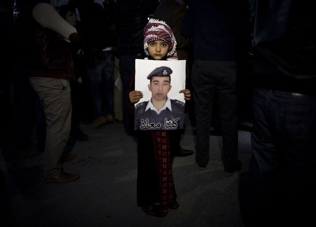 En flicka i Jordanien visar upp en bild på piloten Mu’adh al-Kasasibah som brändes till döds efter att ha tillfångatagits av terrorsekten IS i Syrien. Bilden togs under en sammankomst i Jordaniens huvudstad Amman i februari 2015. Foto: Nasser Nasser/AP/TT