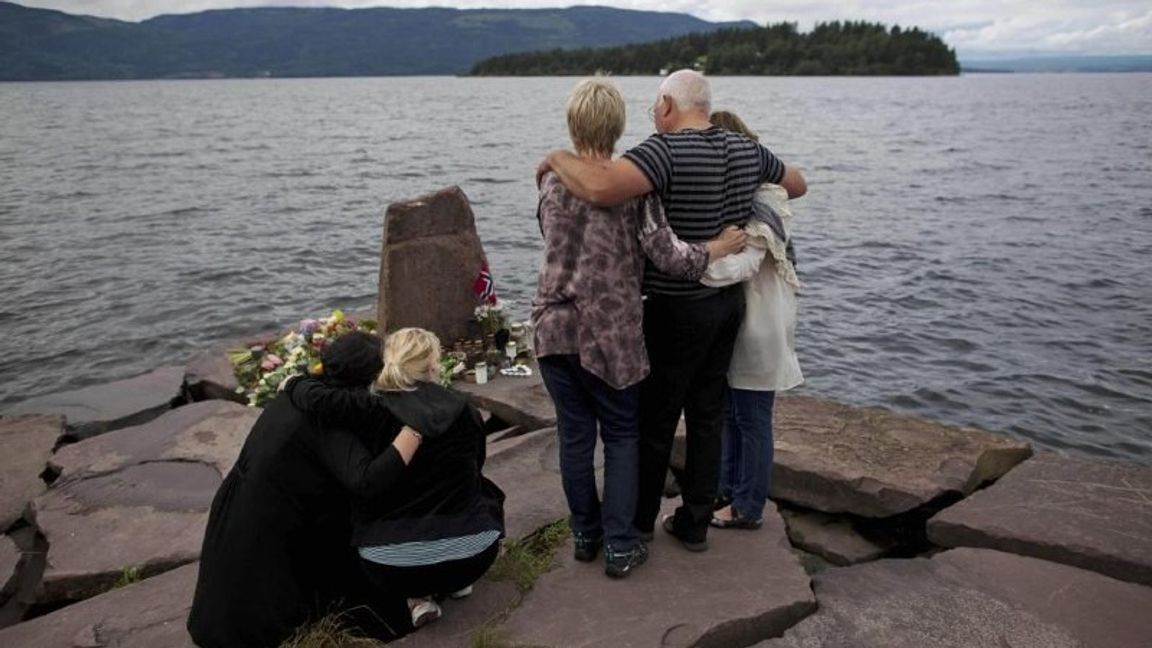 Anhöriga till ett av offren för terrordådet 22 juli 2011 samlas några dagar senare på fastlandet, mittemot ön Utøya, för en tyst minut. Foto: AP Photo/Matt Dunham