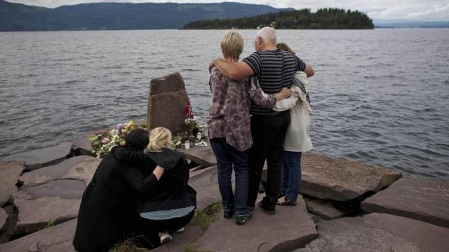 Anhöriga till ett av offren för terrordådet 22 juli 2011 samlas några dagar senare på fastlandet, mittemot ön Utøya, för en tyst minut. Foto: AP Photo/Matt Dunham