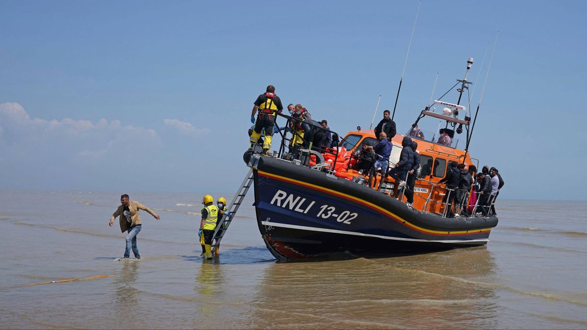 En grupp personer som tros vara migranter stiger i land på Dungeness-udden i södra England efter att ha räddats av en livbåt i Engelska kanalen under tisdagen. Foto: Gareth Fuller/AP/TT.