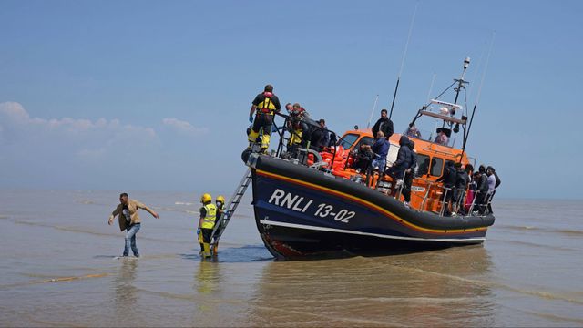 En grupp personer som tros vara migranter stiger i land på Dungeness-udden i södra England efter att ha räddats av en livbåt i Engelska kanalen under tisdagen. Foto: Gareth Fuller/AP/TT.