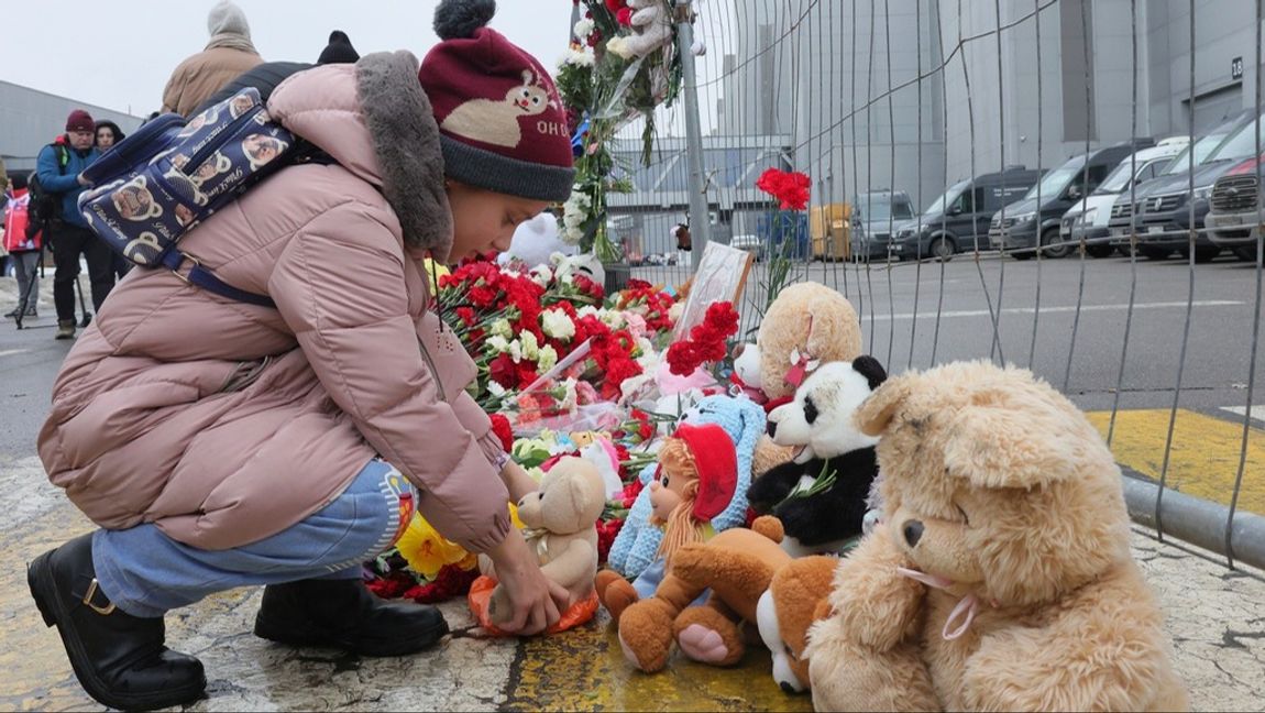 Ett barn lämnar en nalle vid ett stängsel som omgärdar byggnaden där över 130 personer dödades av kamouflageklädda män med automatvapen på fredagskvällen. Foto: VITALY SMOLNIKOV/AP/TT