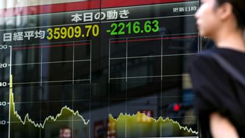 En person går förbi en elektronisk tavla som visar aktiekurser i Tokyo på fredagen. Foto: KYODO NEWS VIA AP/TT