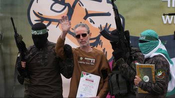 Ohad Ben Ami, en av de tre i gisslan, vinkar i samband med att milismän lämnar över honom till Röda Korset. Foto: Abd al-Karim Hana/AP/TT