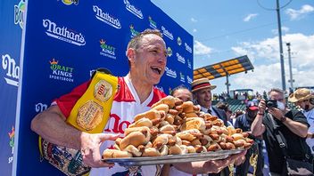 Korvätarmästaren Joey Chestnut jublar med en bricka korv med bröd i famnen efter segern på Coney Island. 76 stycken klämde han i sig. Foto: Brittany Newman/AP/TT.