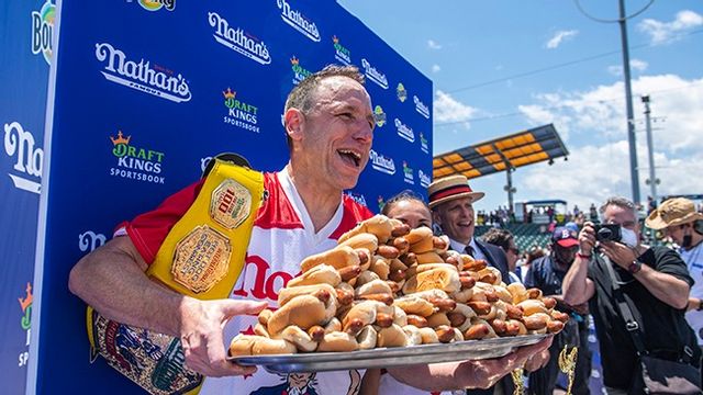 Korvätarmästaren Joey Chestnut jublar med en bricka korv med bröd i famnen efter segern på Coney Island. 76 stycken klämde han i sig. Foto: Brittany Newman/AP/TT.