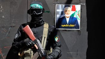 Hamas-terrorist bredvid porträtt av den döda Hamasledaren Ismail Haniyeh. AP Photo/Mohammed Zaatari