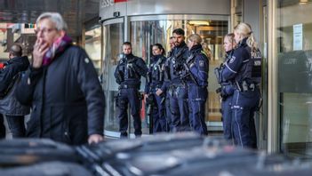 Poliser står framför banken där rånet ägde rum. Foto: Christoph Reichwein/APA via AP/TT