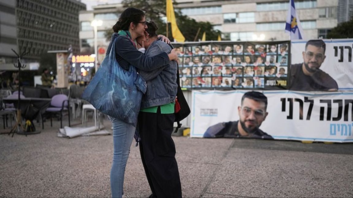 Två kvinnor omfamnar varandra vid en bild av Ran Givli på ”hostage square” i Tel Aviv efter uppfgiften att han kvarlevor hämtats. Bild: AP Photo/Oded Balilty