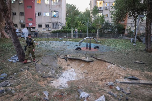 En israelisk soldat betraktar platsen där projektilen slog ned i Tel Aviv-området på lördagen. Tomer Appelbaum/AP/TT