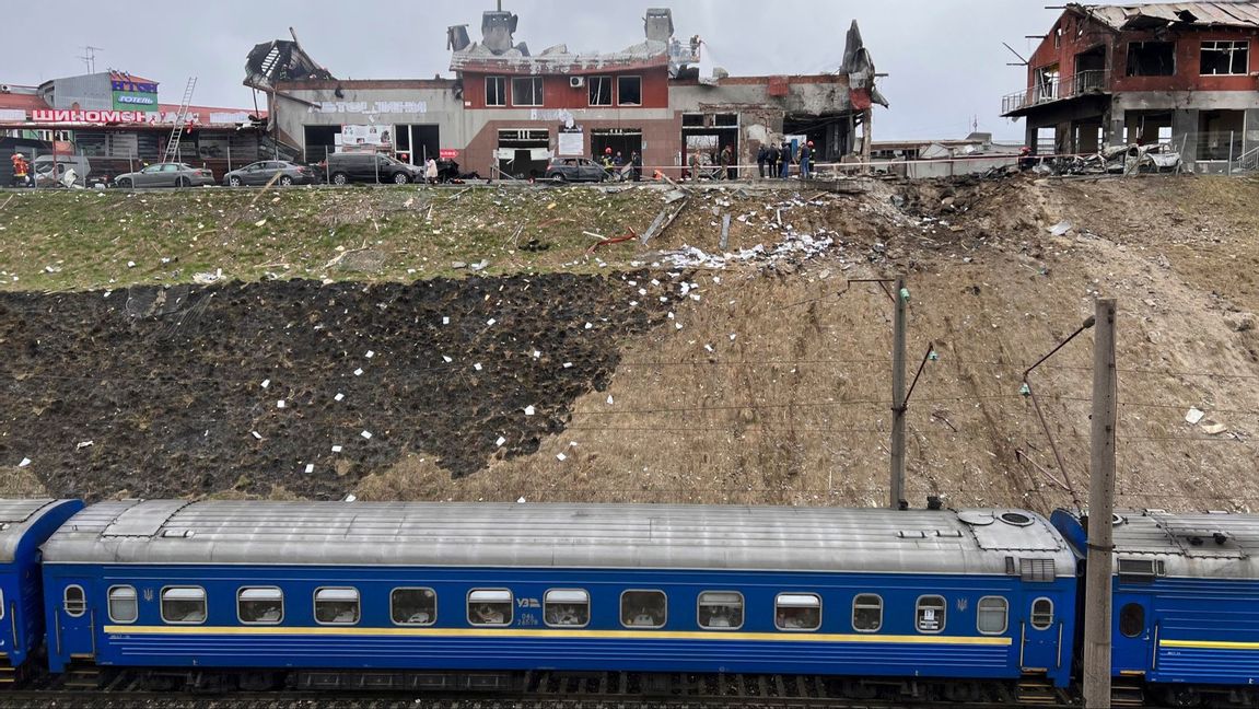 Ett tåg från staden Dnipro passerar räddningstjänstmedarbetare som röjer upp efter en rysk attack i Lviv i västra Ukraina den 18 april 2022. Foto: AP Photo/Philip Crowther 