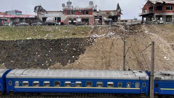 Ett tåg från staden Dnipro passerar räddningstjänstmedarbetare som röjer upp efter en rysk attack i Lviv i västra Ukraina den 18 april 2022. Foto: AP Photo/Philip Crowther 