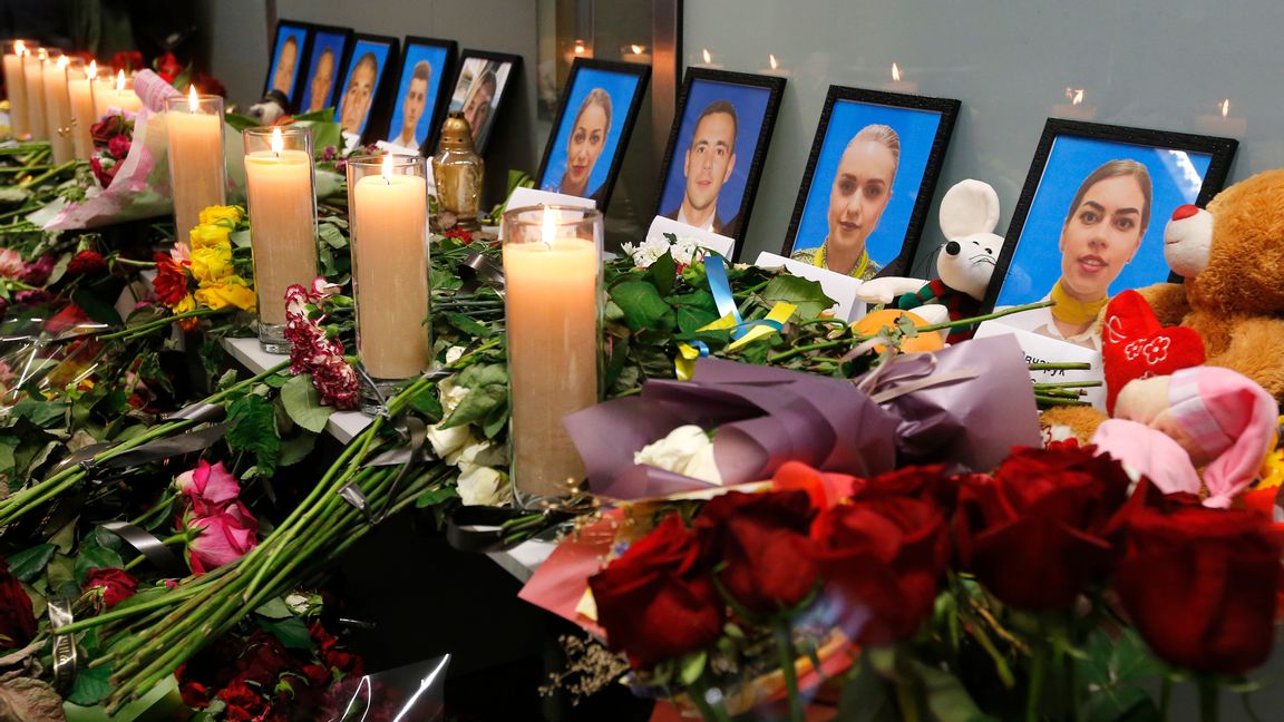 Blommor och ljus vid porträtt av den ukrainska flygplansbesättningen. Foto: Efrem Lukatsky/AP/TT