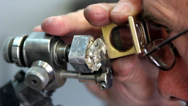 En äkta sydafrikansk diamant inspekteras. Tyvärr visade sig stenarna i KwaHlathi som lockade tusentals diamantletare vara av kvarts. Foto: Denis Farrell/AP/TT