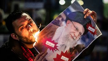 En demonstrant tänder en cigarett med ett porträtt av Irans högsta ledare Ayatollah Ali Khamenei på tisdagen. Bild: Michael Buholzer /Keystone via AP