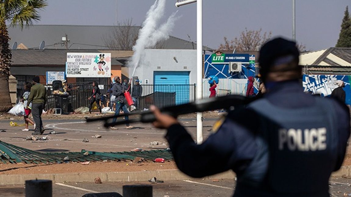 Människor kastar sten på polisen medans de plundrar 
 en butik i Katlehong, i östra Johannesburg. Foto: Themba Hadebe/AP/TT