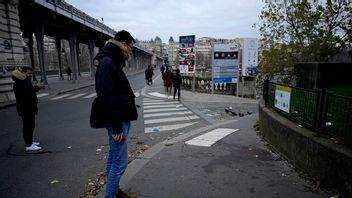 Parisare tittar på blodfläckar efter lördagskvällens terrorattack. Foto: Christophe Ena/AP/TT