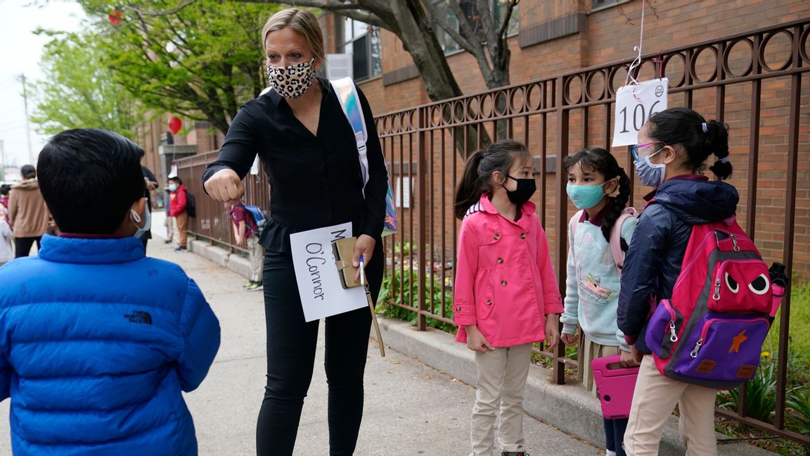 Barn i New Jersey, USA, hälsas av sin lärarinna. Förra veckan återvände de till skolan efter en längre tids distansundervisning. Foto: Seth Wenig/AP/TT.